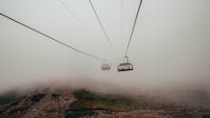 缆车在薄雾笼罩的山区穿行，于浓雾中移动，营造出宁静而神秘的氛围