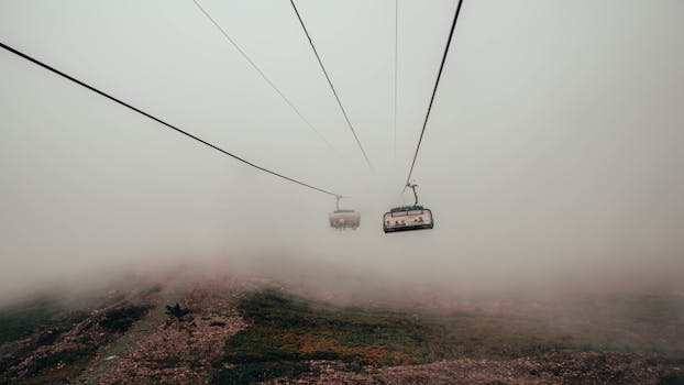 缆车在薄雾笼罩的山区穿行，于浓雾中移动，营造出宁静而神秘的氛围