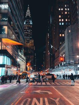 Vibrant nighttime cityscape of New York featuring bustling street and iconic Chrysler Building.