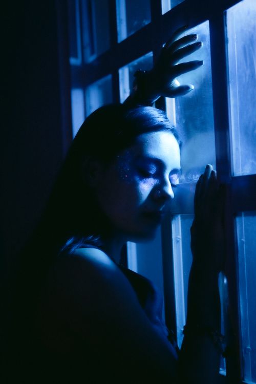 Free Artistic portrait of a woman with blue lighting, conveying a serene and contemplative mood. Stock Photo