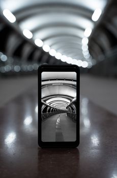 Black and white smartphone photo capturing a modern tunnel with bokeh effect.