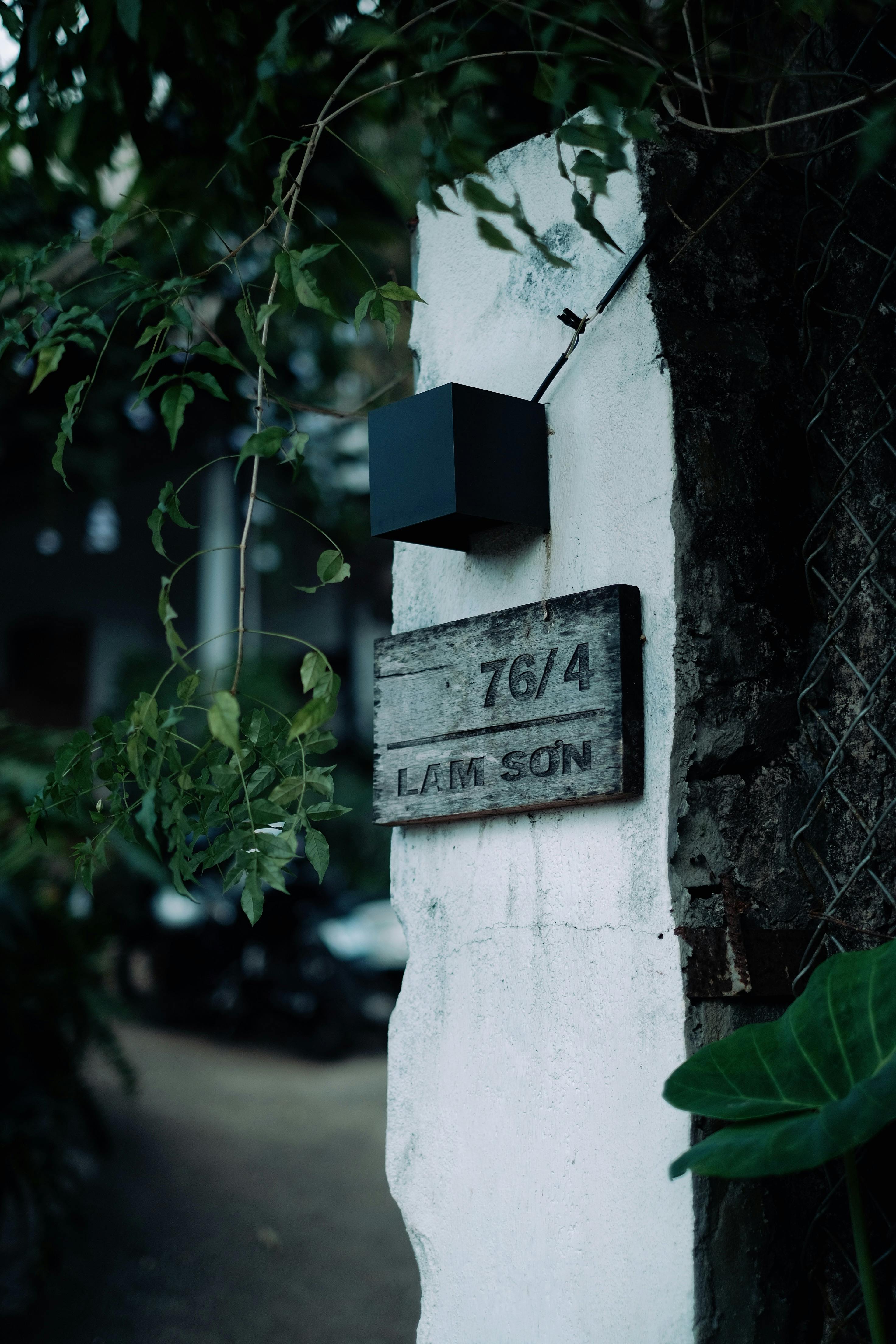 Outdoor street sign on rustic wall, surrounded by greenery in Lam Son area.