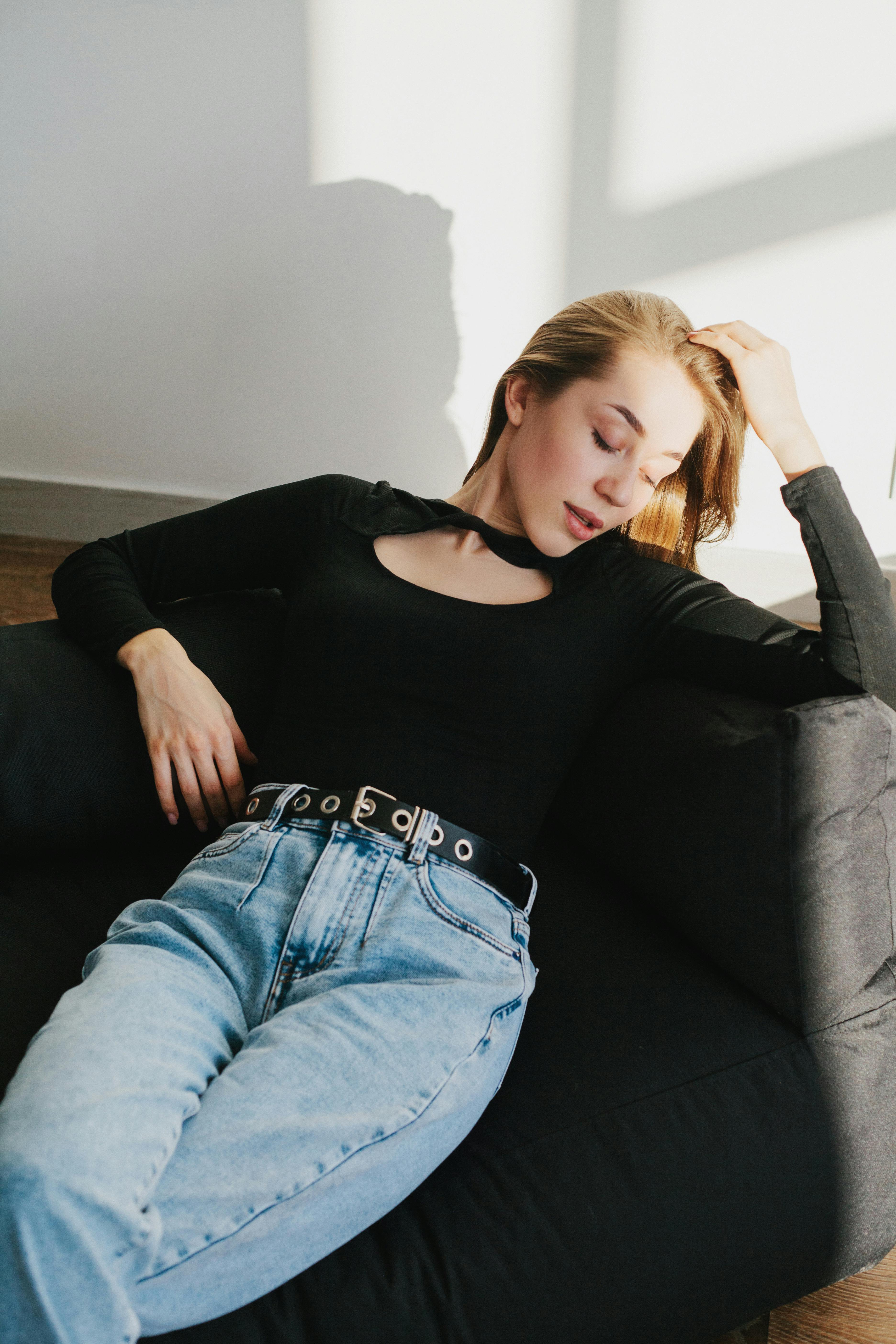 Young woman in casual outfit lounging on a sofa, enjoying a moment of relaxation.