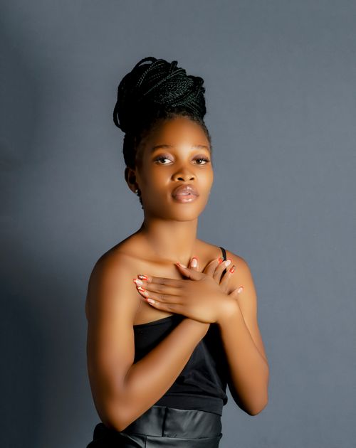 Free Portrait of a young woman with braided hair against a gray background, exuding elegance. Stock Photo
