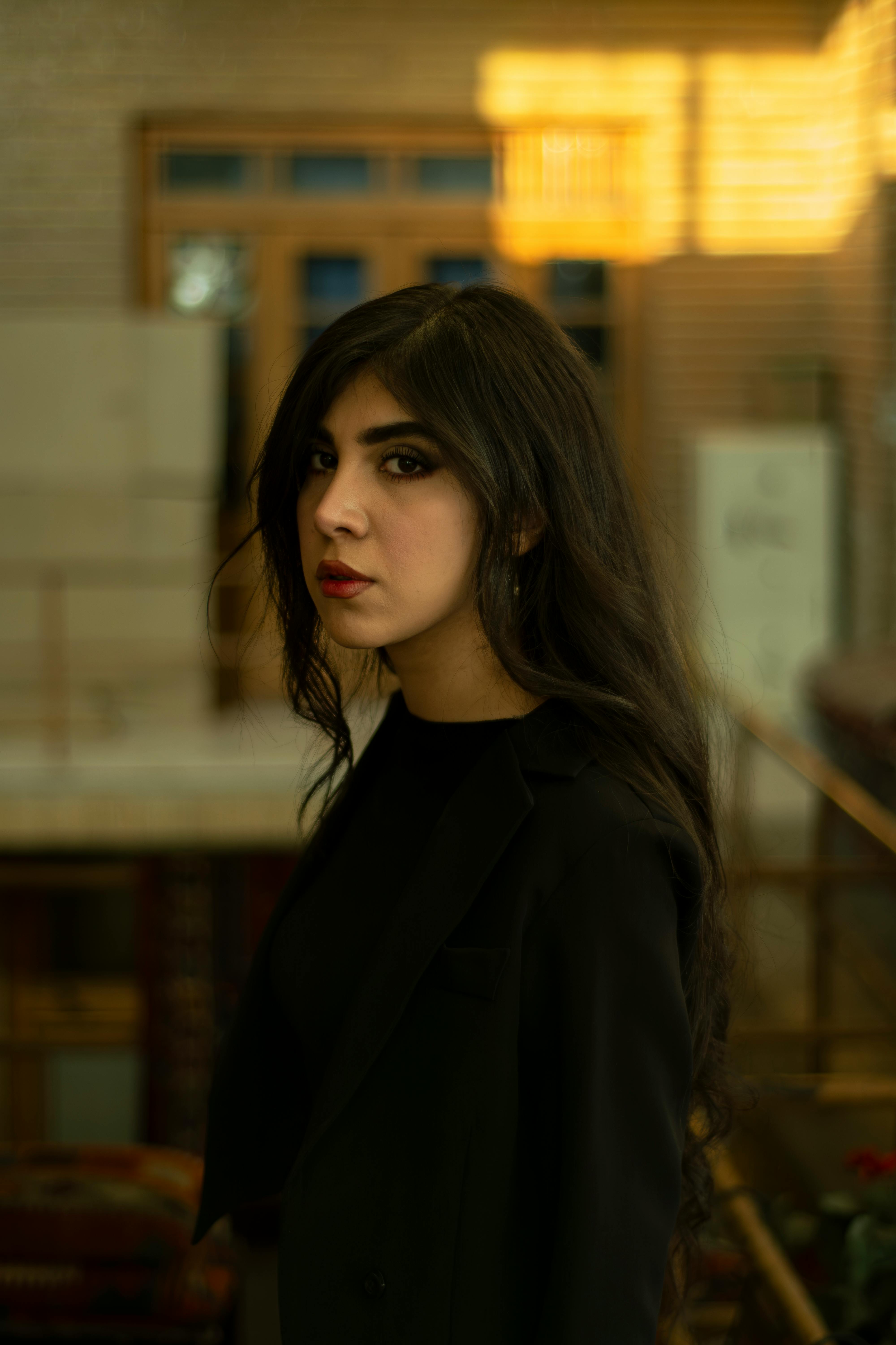Side profile portrait of a woman with long black hair in a stylish setting.