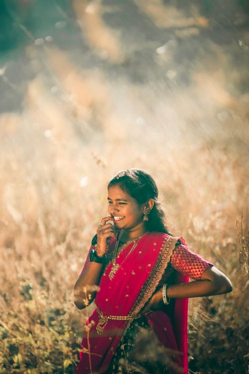 Free A joyful girl in a vibrant sari enjoying nature in a sunny meadow. Stock Photo