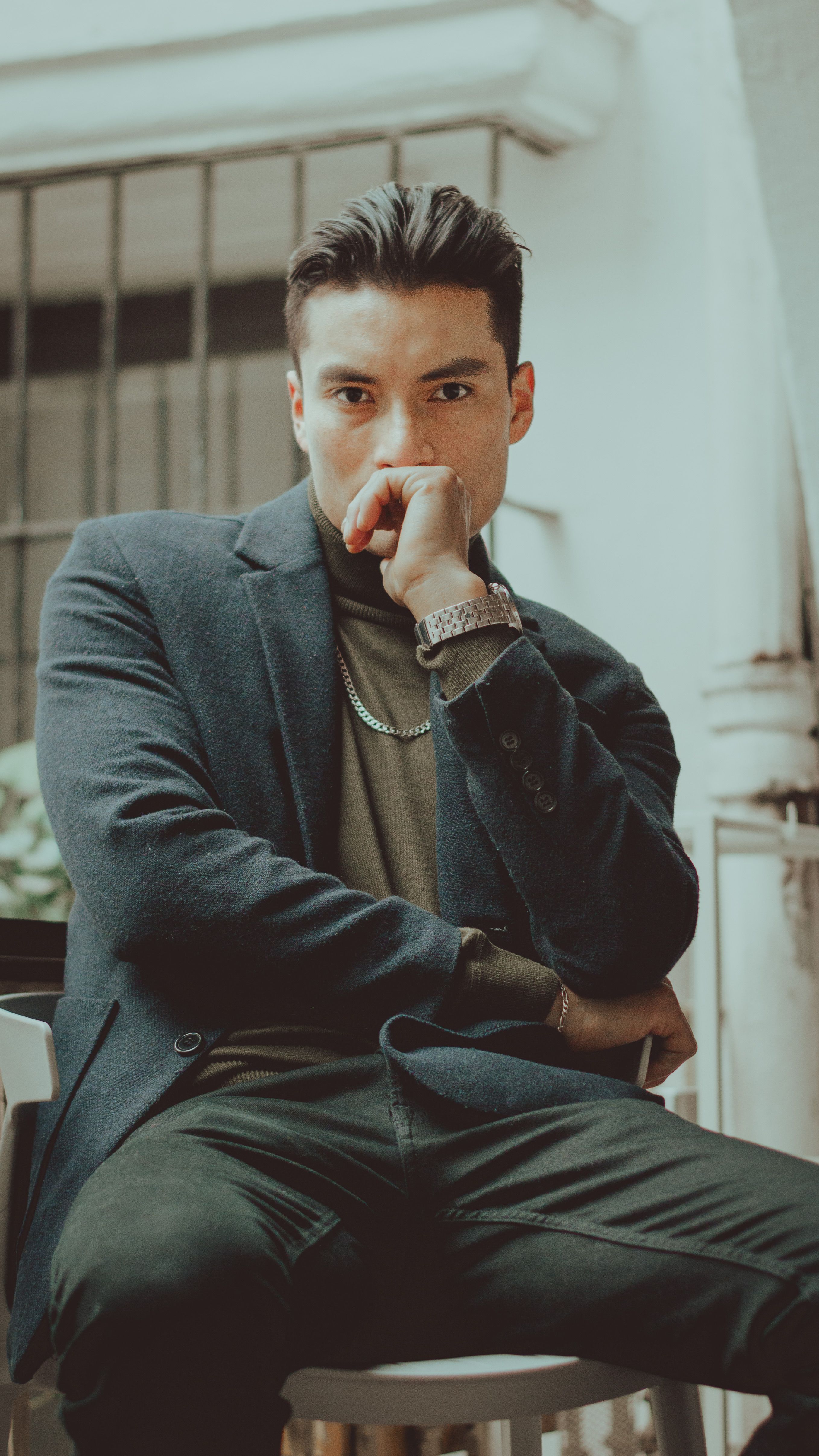 Fotomural Hombre joven confiado con ropa informal elegante en un interior, pose pensativa.