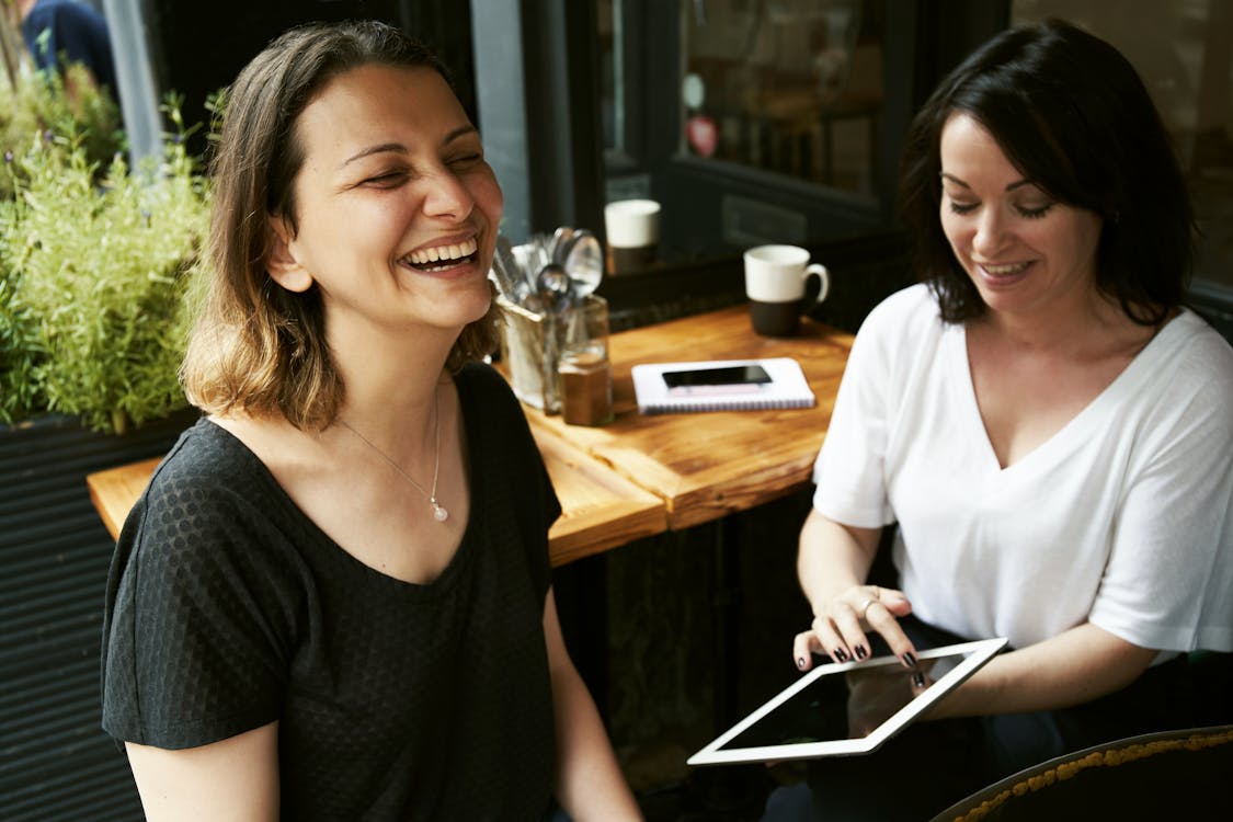 Photo of Two Women Sitting While Laughing