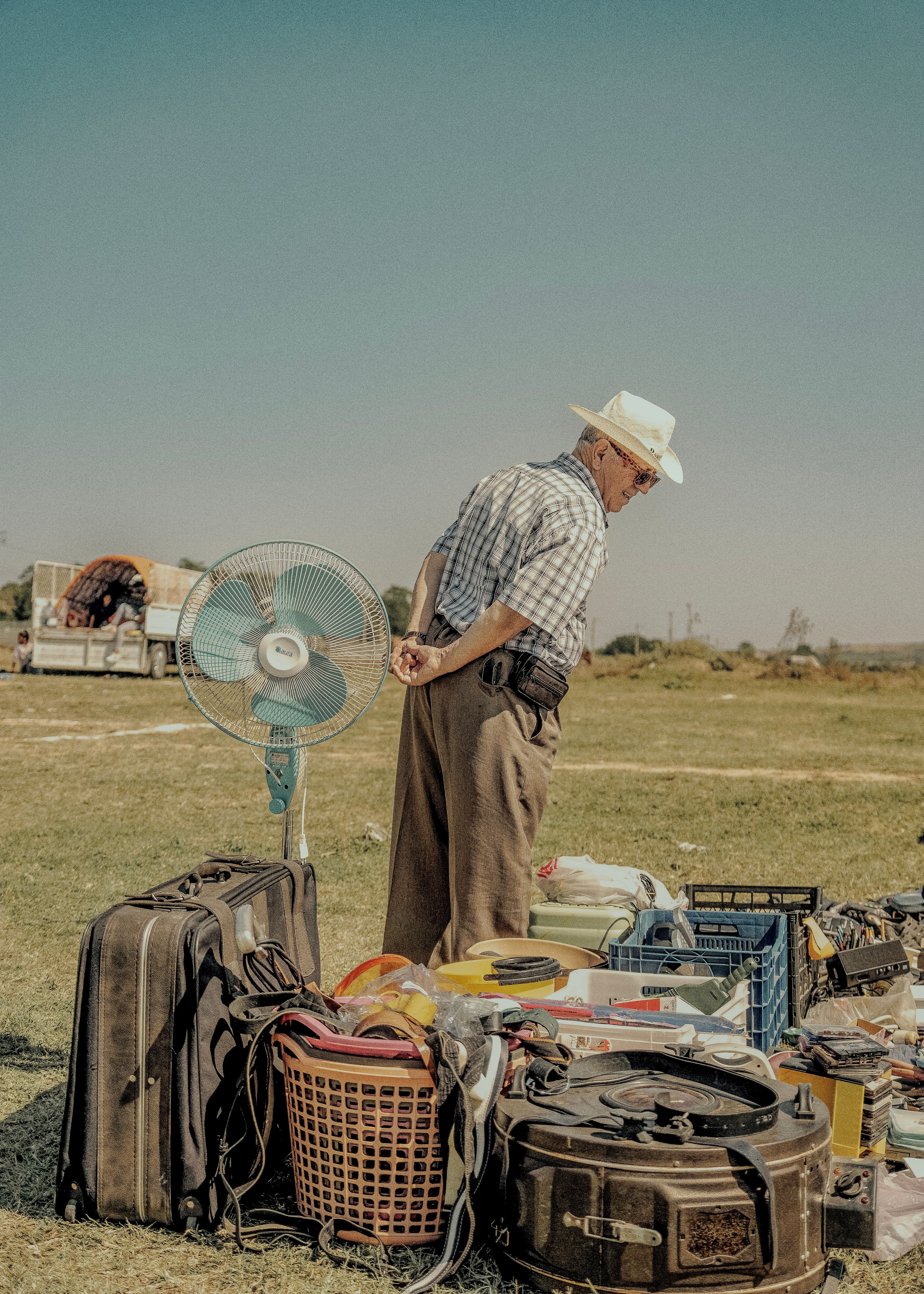 Senior examining vintage items at a sunny outdoor flea market.