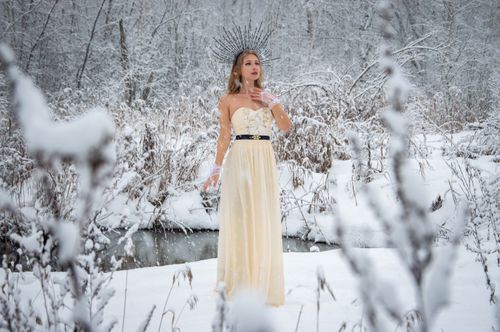 Free Elegant woman in a snowy forest wearing a gown and crown, capturing a serene winter scene. Stock Photo