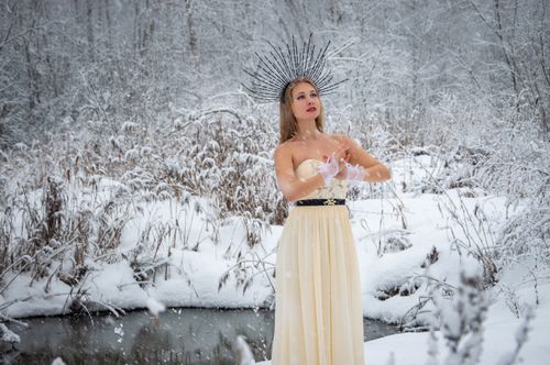 Free Woman in gown with ethereal headdress stands elegantly in a snowy landscape. Stock Photo