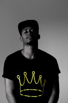 这是一张黑白肖像，画面中一名男子身穿印有皇冠图案的衬衫，整体色彩非常克制