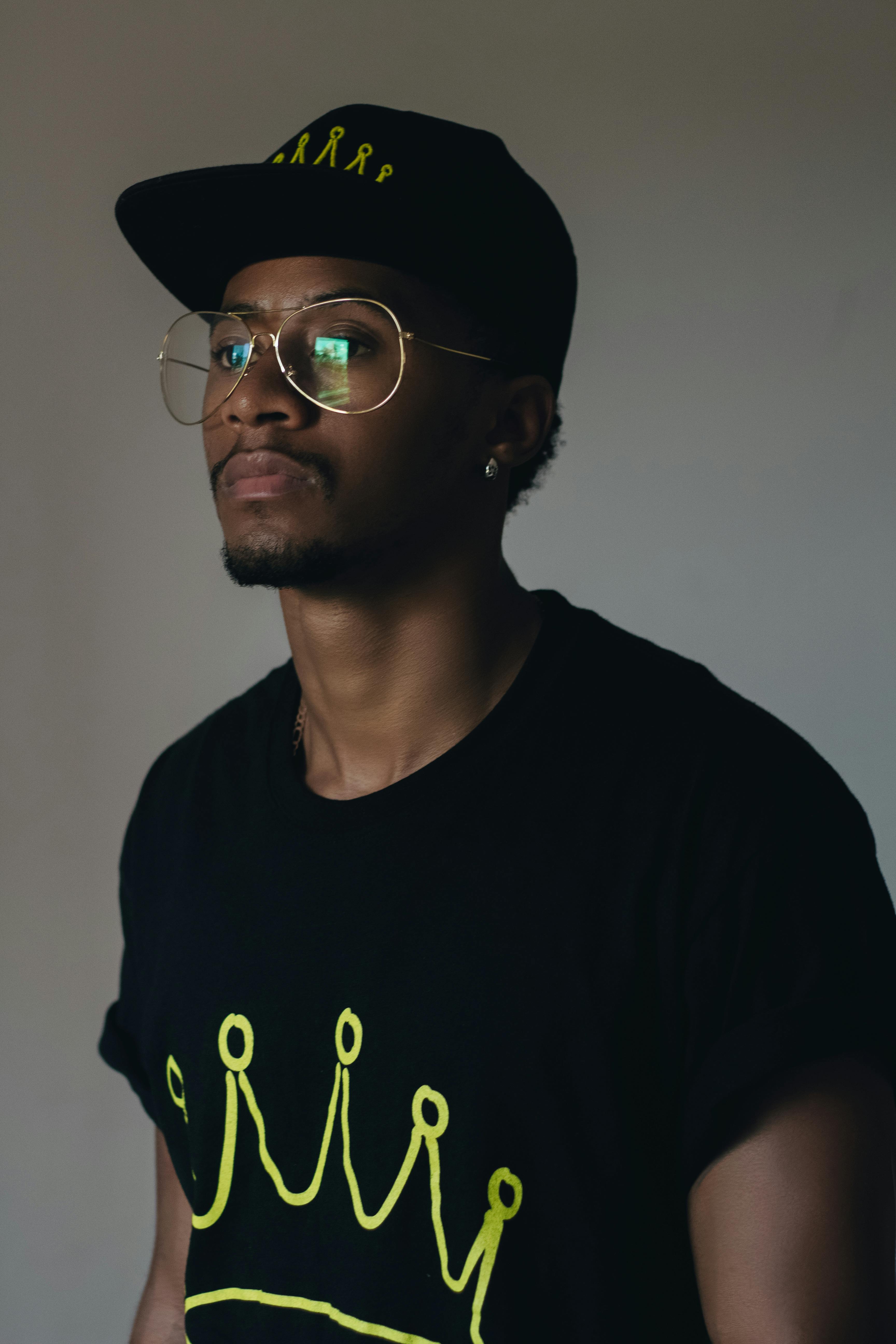 man wearing black crew neck shirt and black cap