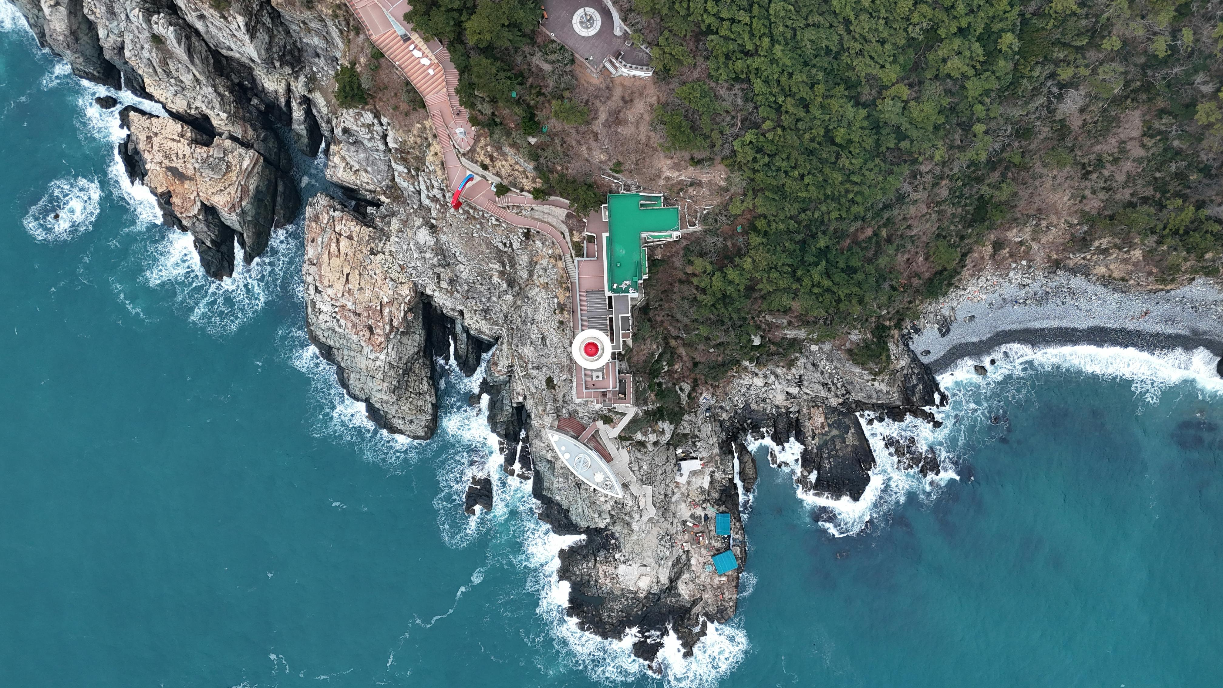 A breathtaking aerial view of the rocky coastline in Busan, South Korea, showcasing vibrant colors.