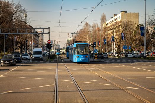 Blue tram traversing a busy street in Zagreb, Croatia's urban landscape.