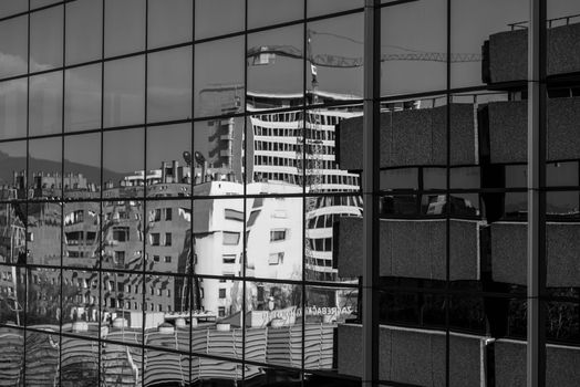 A black and white photo capturing Zagreb's urban landscape reflected in glass windows.