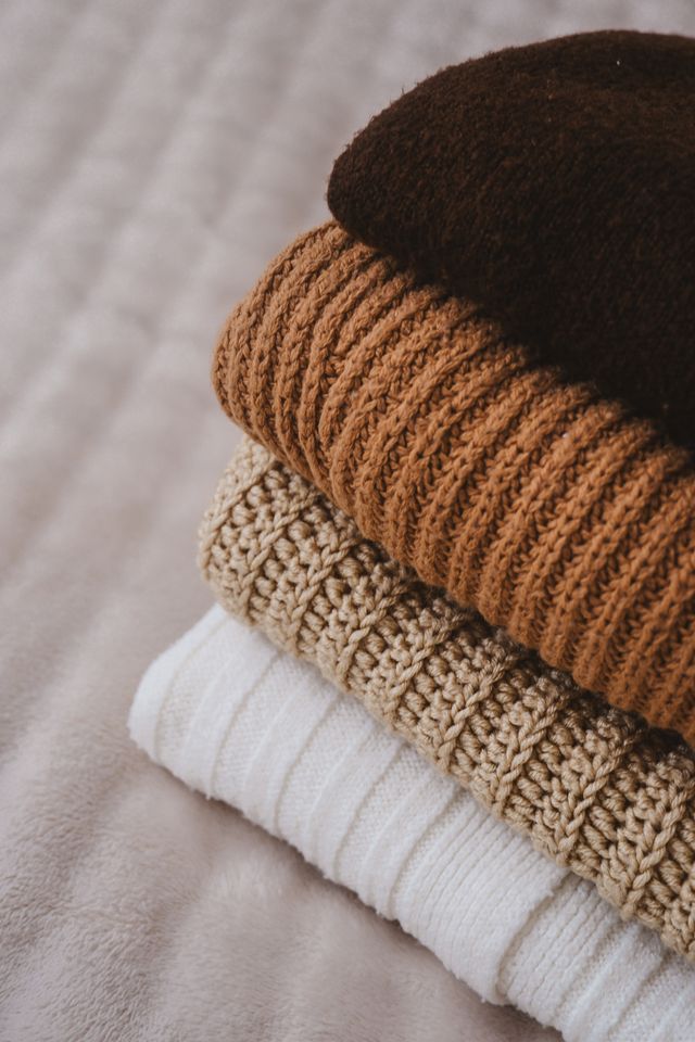 Stack of folded knitted sweaters in neutral tones, photo by Gülşah Aydoğan on Pexels