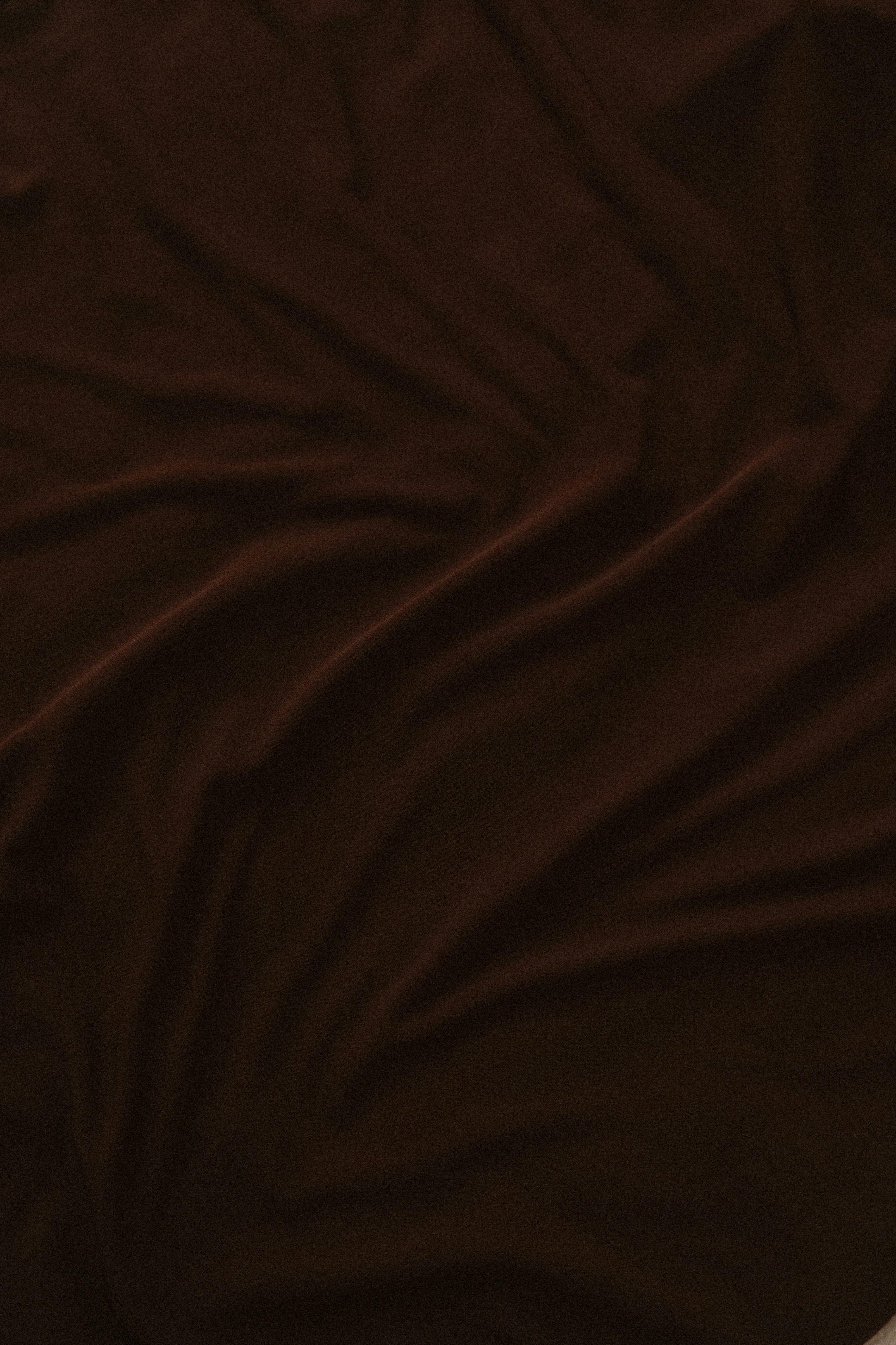 bezplatná Detail tmavě hnědé látky s elegantními záhyby a jemnou texturou. Základová fotografie