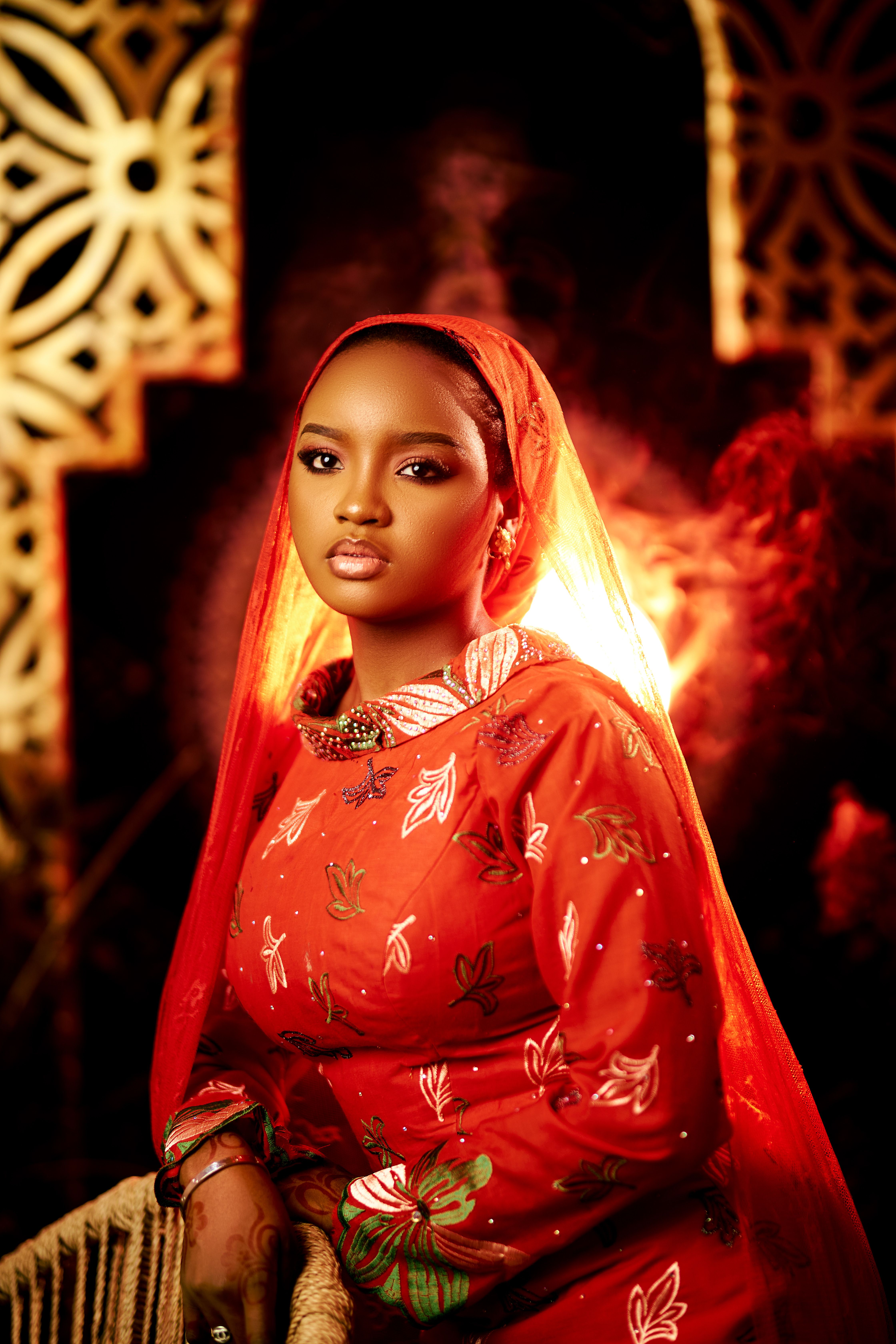 Portrait of a woman in elegant red traditional attire with intricate patterns.