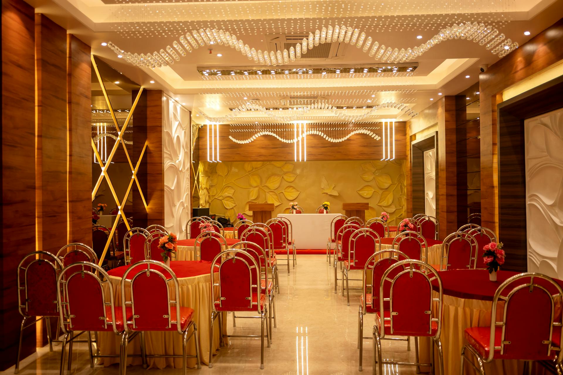 Luxurious hotel conference room with red chairs and ornate ceiling design, perfect for events.