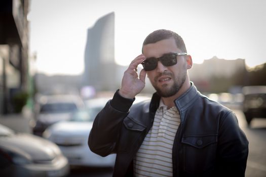 Casual man in sunglasses standing confidently on urban street in Baku.