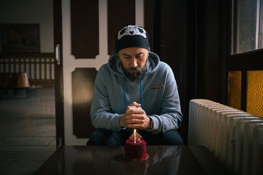 A man reflects on his birthday with a cake at a cozy indoor setting in Istanbul.