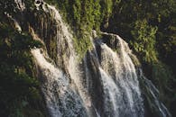 沿着绿树成荫的岩壁，宁静的瀑布流淌而下，营造出一片宁静的自然风光