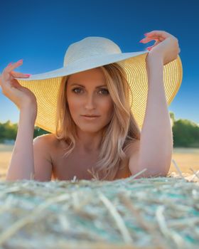 Portrait of a woman in a sun hat in a sunny field, exuding elegance and warmth.