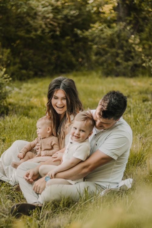 Free Candid family portrait capturing parent-child bonding in a serene outdoor setting. Stock Photo