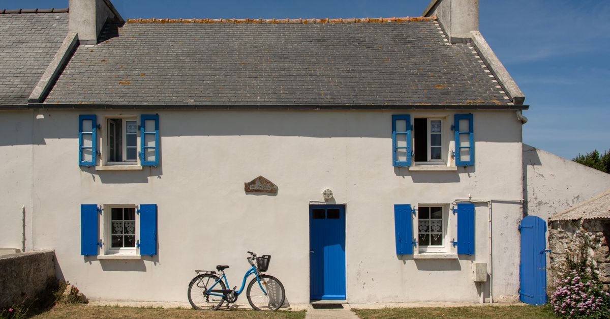 Picturesque house with blue shutters and bicycle in Ouessant, France.