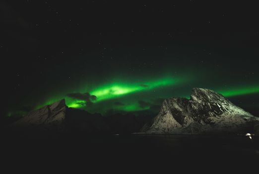 Captivating aurora borealis lighting up the night sky over snow-covered mountains.