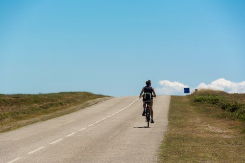 Free A lone cyclist rides uphill on a sunny day, capturing the essence of a solo adventure. Stock Photo