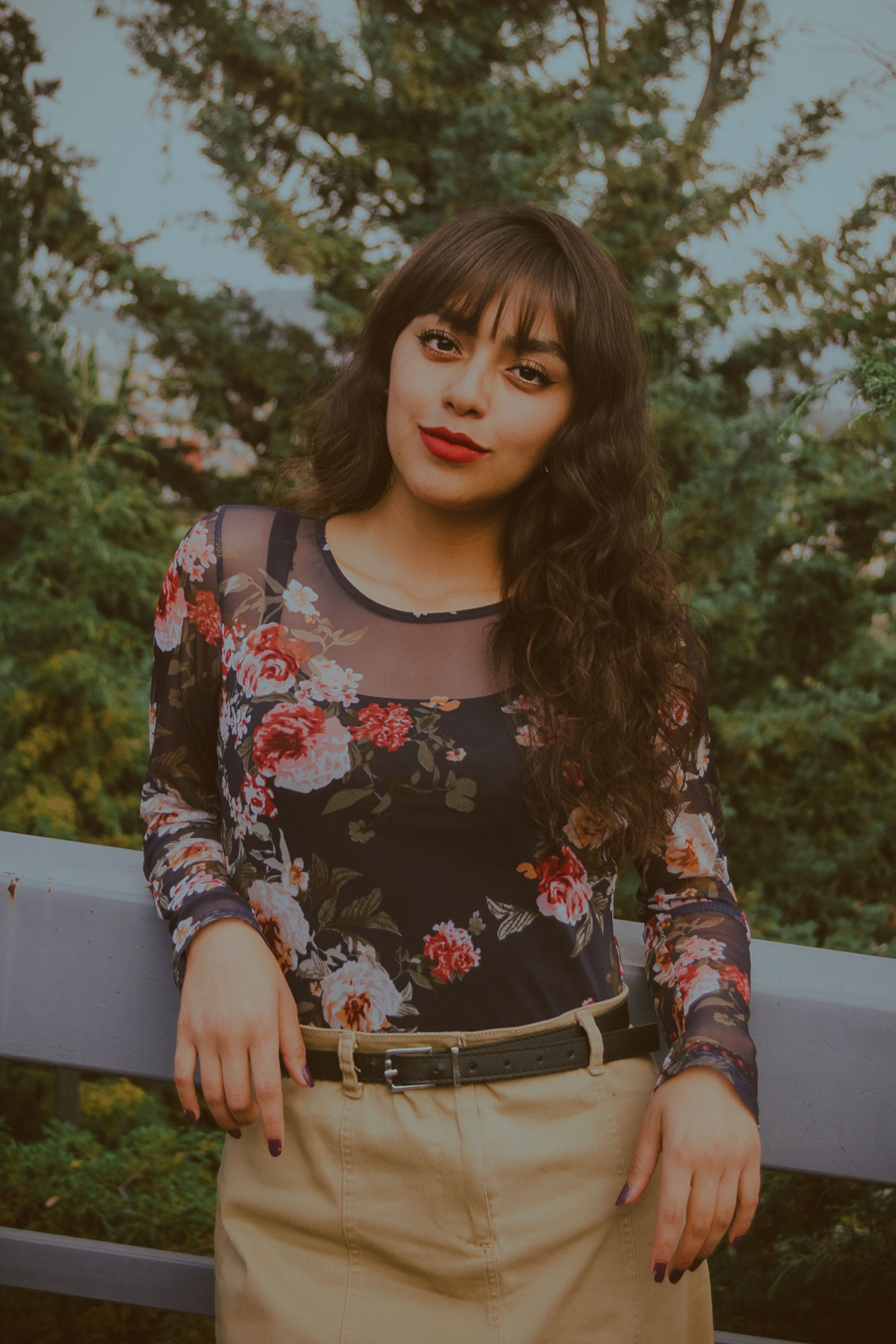 Woman in Floral Top Posing Outdoors with Greenery · Free Stock Photo