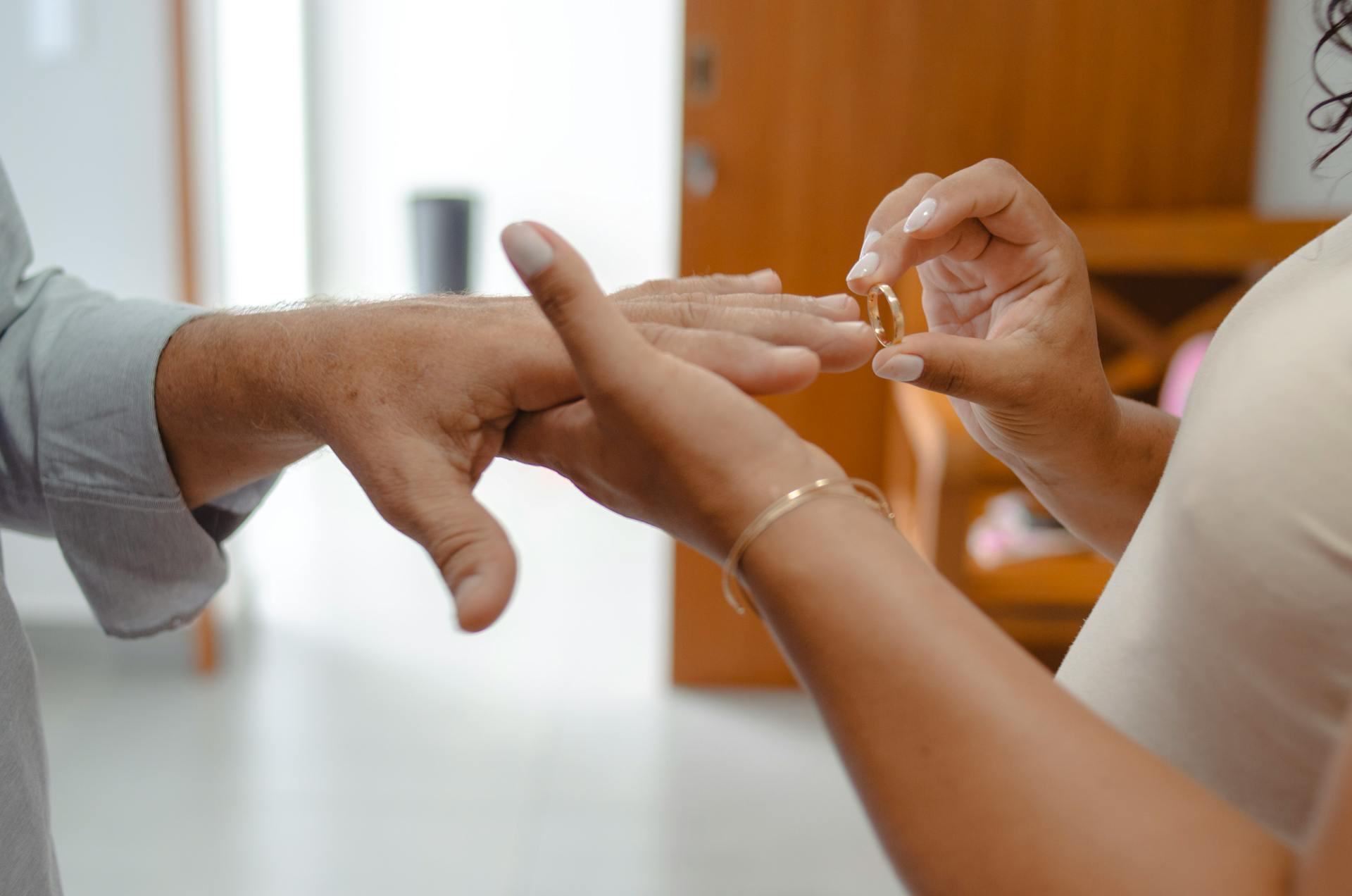 Close-up of hands exchanging rings in a warm indoor setting, symbolizing love.