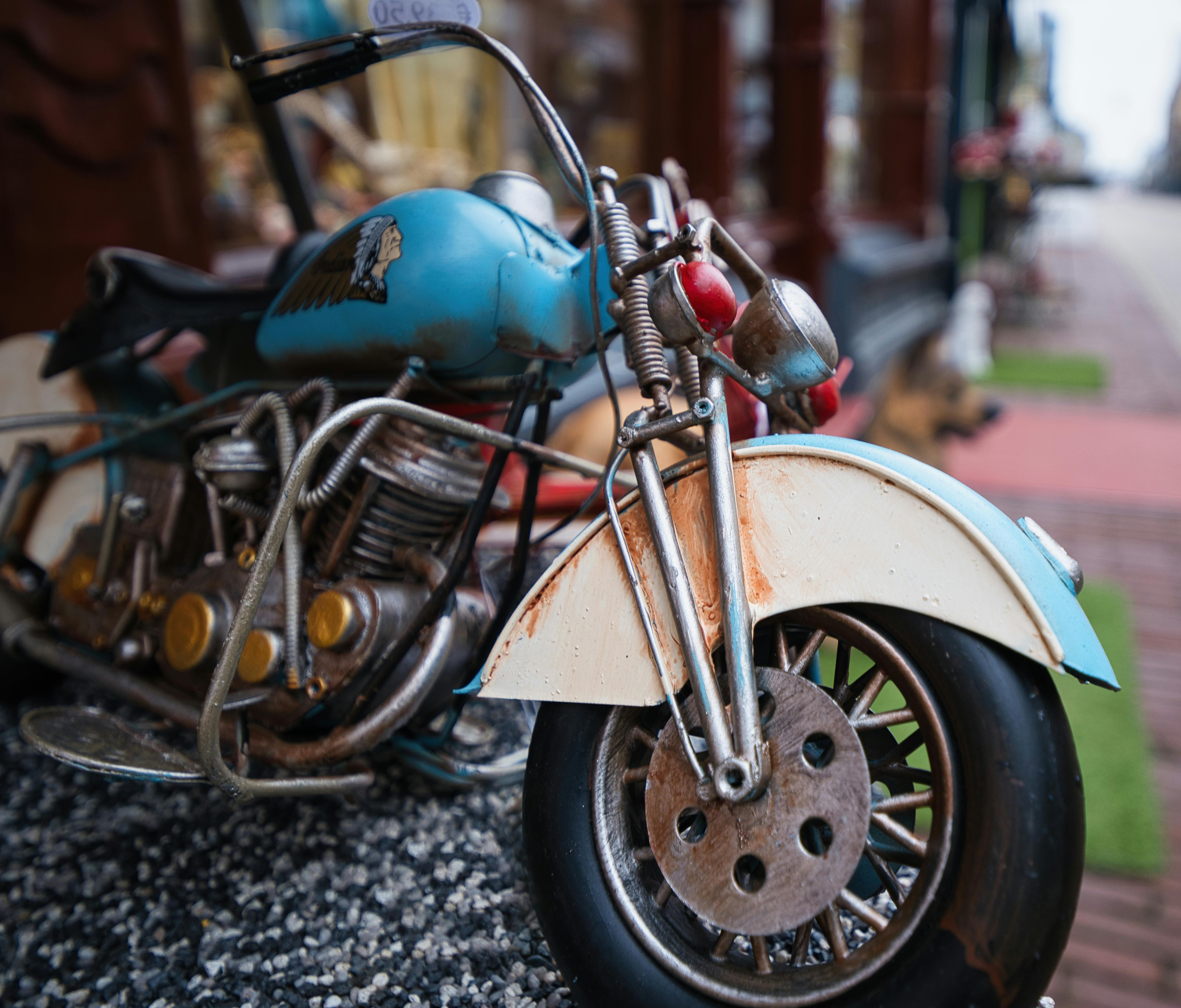 Zadarmo Detailný záber vintage modro-bieleho hračkárskeho modelu motocykla vystaveného vonku na textúrovanom povrchu. Fotka z fotobanky