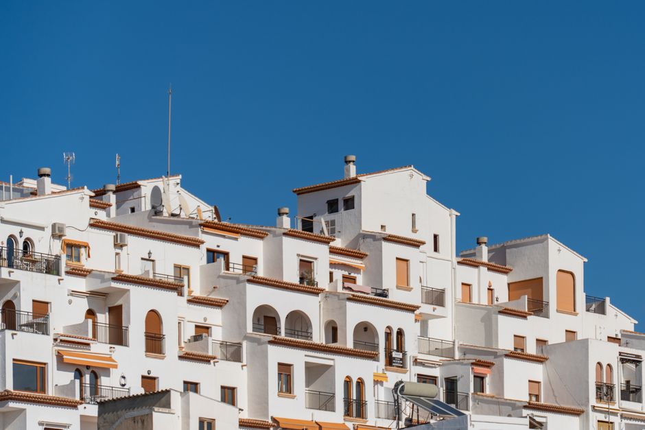 Edificios tradicionales blancos mediterráneos contra un cielo azul claro en Moraira, España.