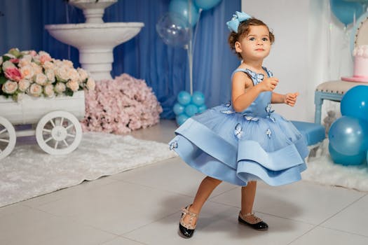 Adorable child in a blue dress enjoying a festive indoor celebration with floral decorations.