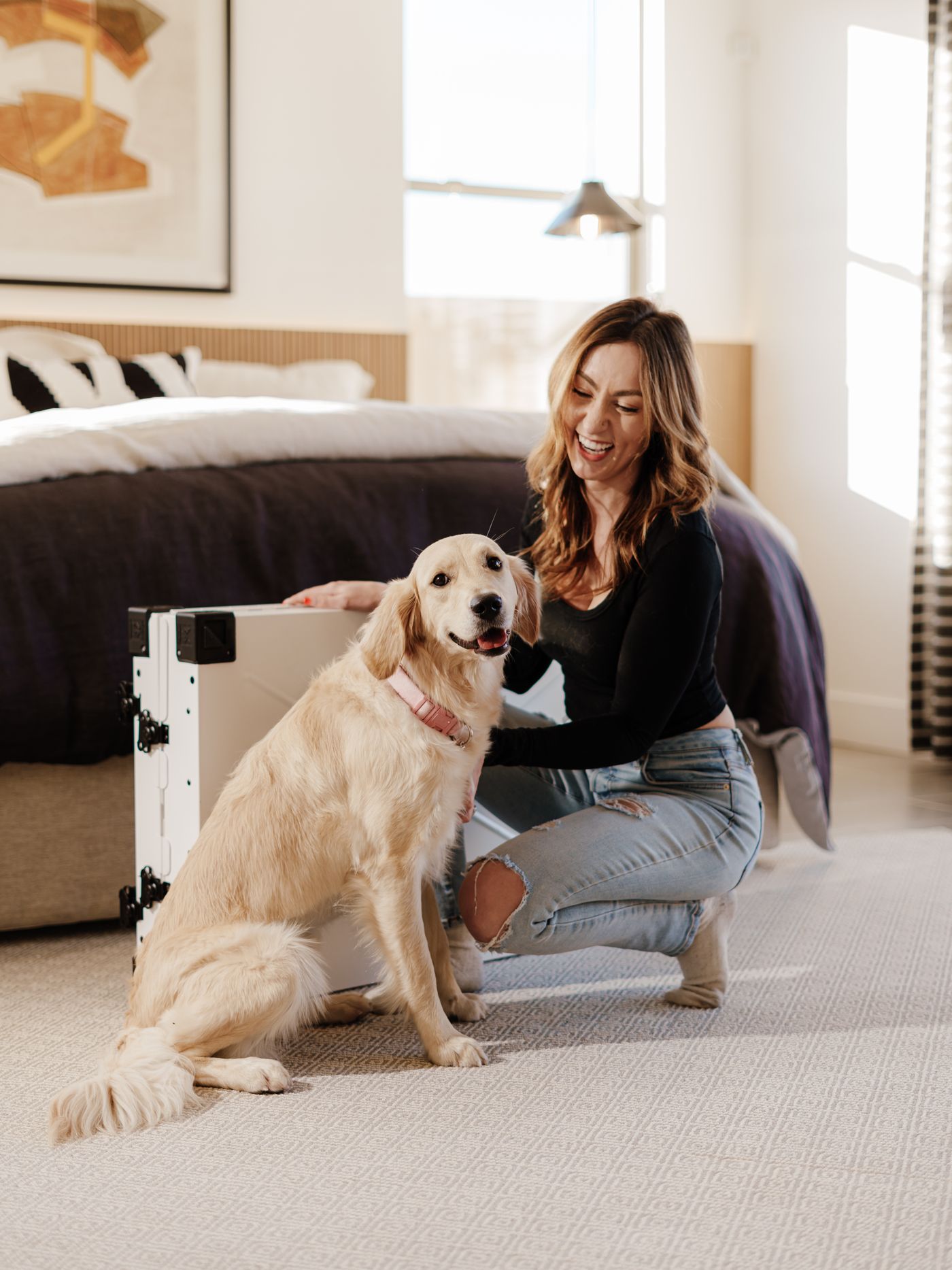 A smiling woman sharing a joyful moment with a golden retriever inside a bright, comfortable home