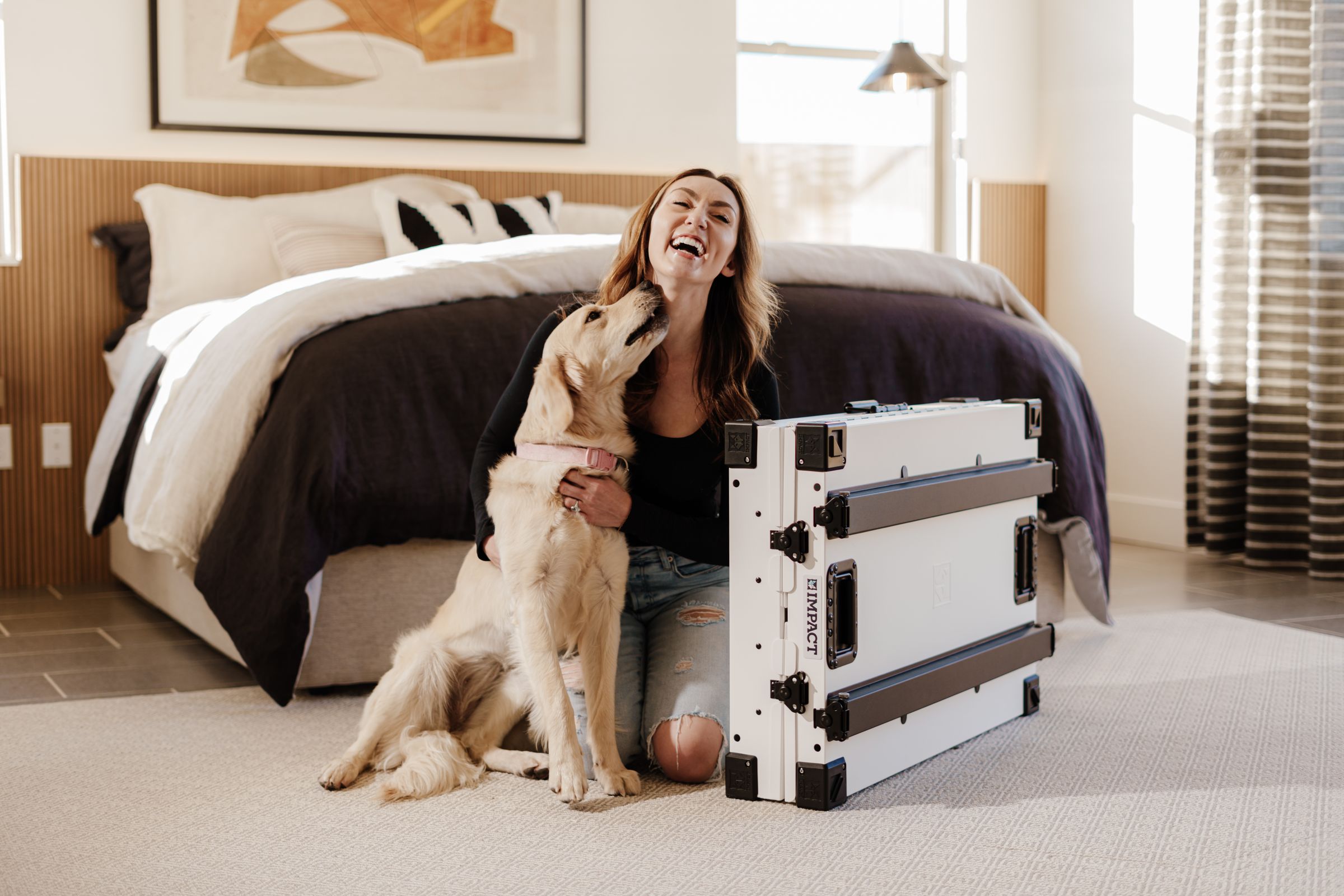 Joyful woman relaxing with her dog near a smart crate in a cozy bedroom