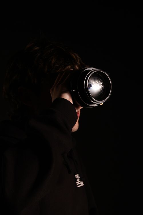 Free Moody portrait of a man observing through a camera lens, highlighting contrast and shadows. Stock Photo
