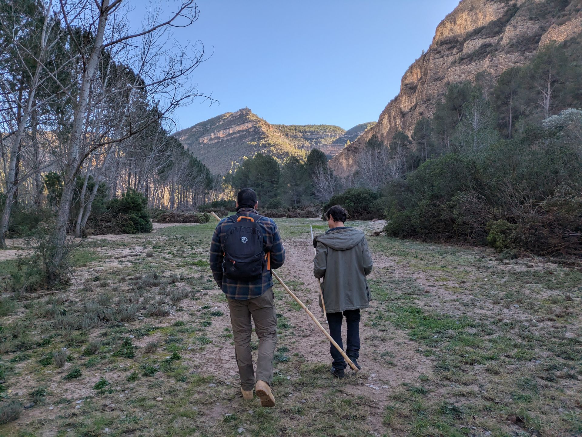Two people hiking in a picturesque Spanish mountain landscape during the day.