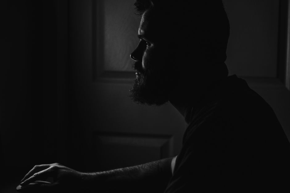 Silhouette of a bearded man in low light creating a mysterious atmosphere.