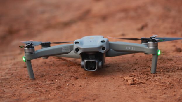 A detailed shot of a gray drone resting on sandy ground in daylight, showcasing technology.
