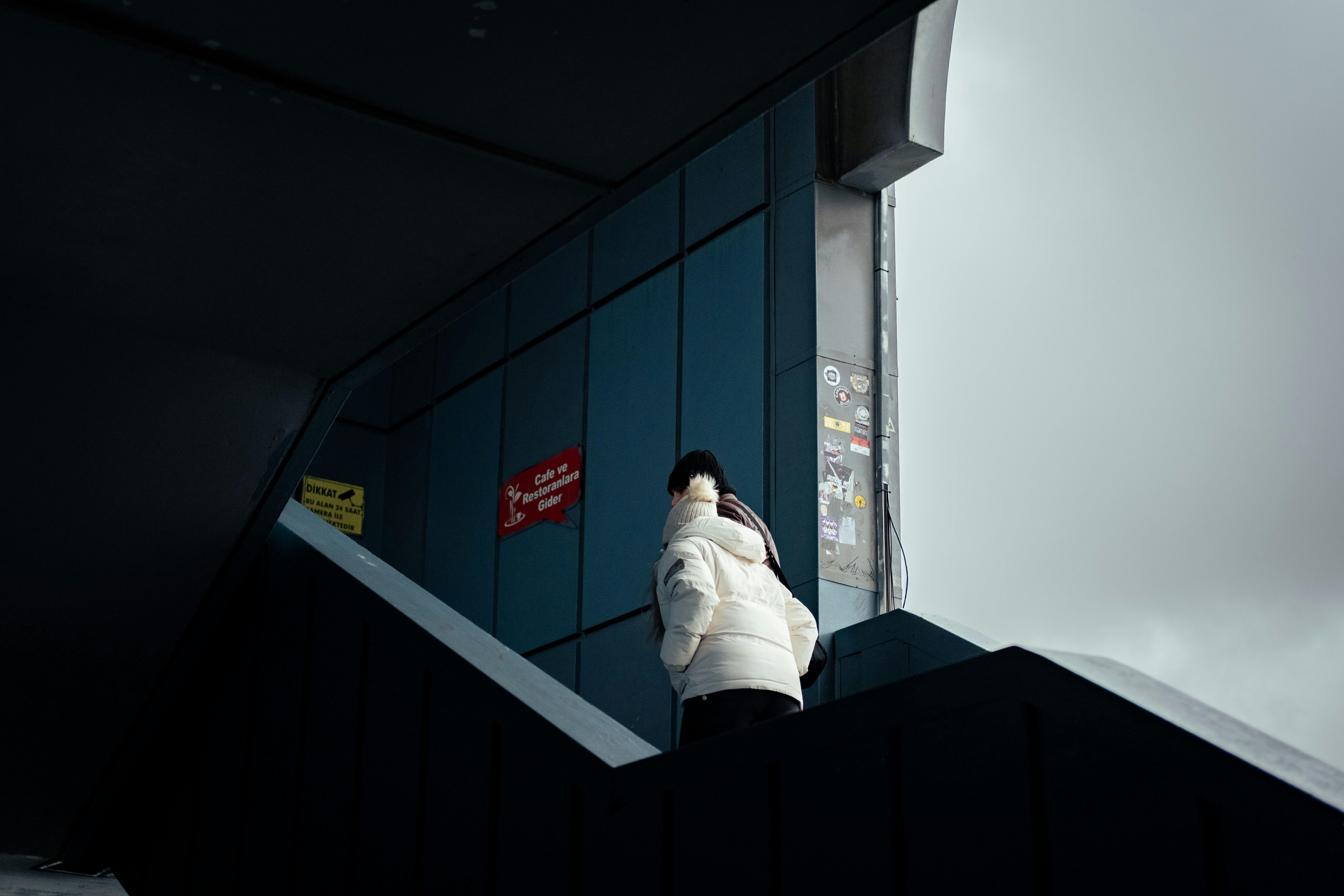 bezplatná Osoba v zimním kabátě šplhající po městském schodišti s moderní architekturou. Základová fotografie