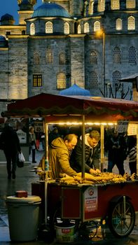 Street vendors selling roasted corn at a night market near a historic mosque.