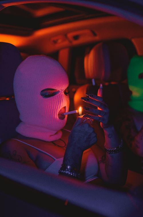 Free Two masked individuals in a car under neon lighting, creating a mysterious, dramatic vibe. Stock Photo
