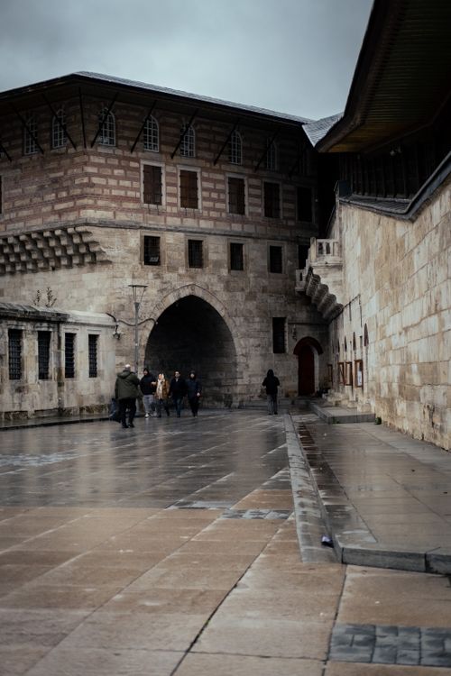 Free Stone fortress with arched entrance under cloudy sky, people walking. Stock Photo