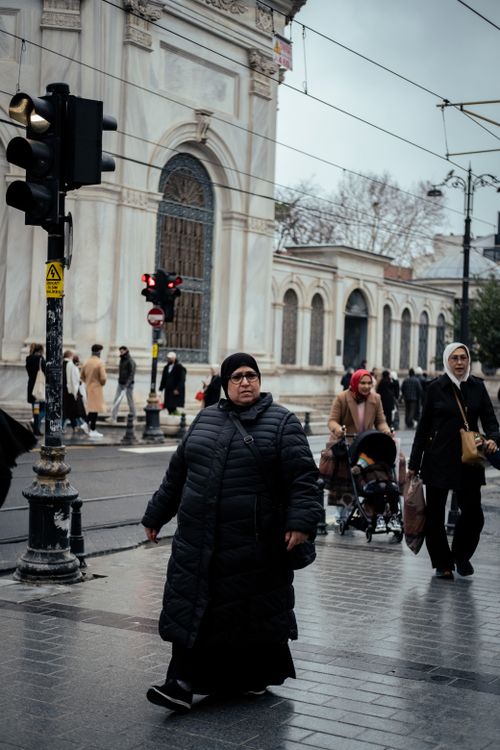 Free People walking on a city street under overcast sky, creating a moody urban scene. Stock Photo