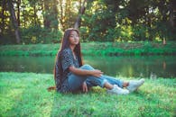 一位年轻女子身着休闲装，坐在宁静的河边