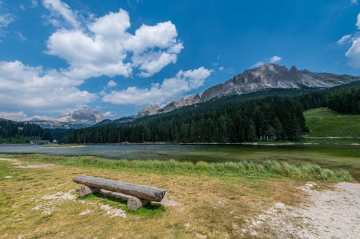Tranquil landscape of a lake with a mountain backdrop in Veneto, Italy, under a vibrant blue sky.